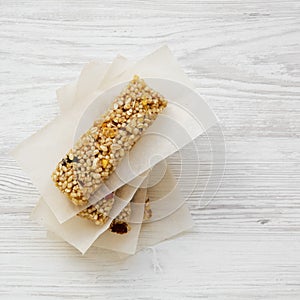 Granola bars on baking sheet over white wooden surface, view from above. Flat lay