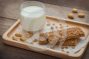 Granola bars and glass of milk on wooden plate