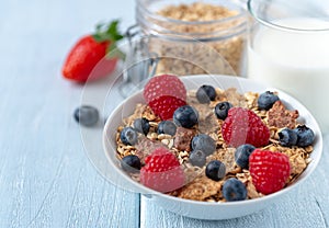 Granola with blueberries and raspberries in white bowl on dark white desk
