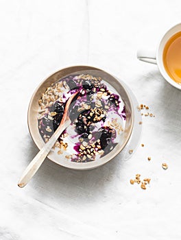 Granola, blueberry sauce greek yogurt and green tea on light background. Healthy breakfast concept