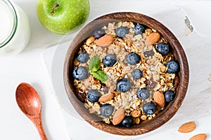 Granola bowl with blueberries and almond nuts on white table