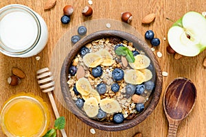 Granola bowl with blueberries, banana slices, apple, honey and milk