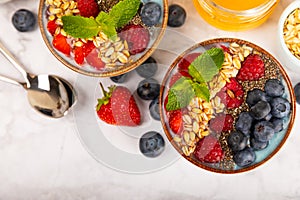Granola bowl with yogurt and fresh almonds, blueberries, raspberries,peach and strawberries on kitchen table.