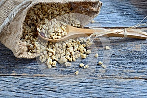 Granola in Burlap Sack Spilling onto Wood Background