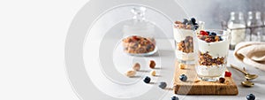 Granola, cereal breakfast banner. Blueberry parfait in glasses on wooden board on gray background. Cafe, restaurant, confectionery