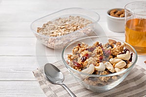 Granola with dried fruits and nuts in bowl on white wooden table