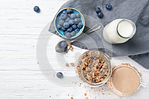 Granola muesli, milk and ripe blueberries, healthy breakfast concept, wooden background, top view