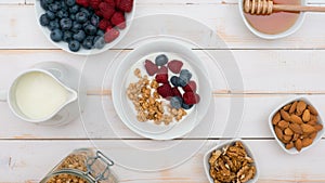 Granola with natural yogurt, fresh blueberries, nuts and honey, delicious breakfast or dessert, top view. Healthy eating