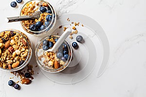 Granola with nuts, yogurt and berries in jar. Breakfast parfait with muesli, yoghurt and blueberries, white background