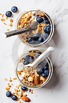 Granola with nuts, yogurt and berries in jar. Breakfast parfait with muesli, yoghurt and blueberries, white background