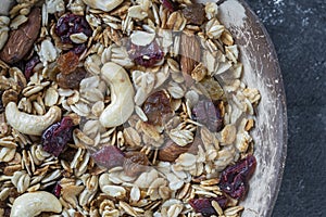 Granola with oatmeal, dried fruit, honey, raisins, dry cranberry, almond and cashew nuts in a coconut bowl, close up