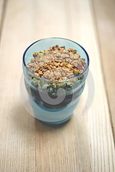 Granola Parfait in Blue Tumbler on Wooden Surface