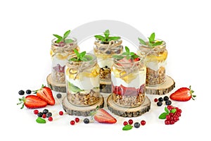 Granola, slices of different fresh fruits, yogurt, honey in jars isolated on white background.