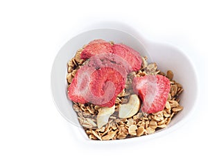 Granola with strawberry in a heart-shaped bowl isolated.