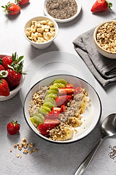 Granola with yogurt, fresh strawberries, kiwi, banana and nuts, seeds. Healthy breakfast.