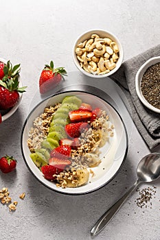 Granola with yogurt, fresh strawberries, kiwi, banana and nuts, seeds. Healthy breakfast.