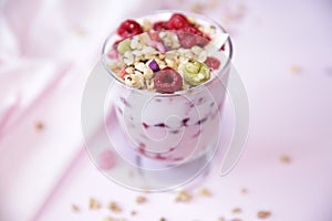 Granola yogurt parfait with fresh raspberry berries on a light pink background. Healthy food. With copy space for text.