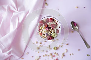 Granola yogurt parfait with fresh raspberry berries on a light pink background. Healthy food. With copy space for text. Flat lay