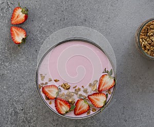 Granola, yogurt, strawberry in bowl on grey background. Bowl of granola with yogurt and fresh berries, top view.