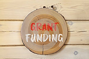 Grant funding symbol. Concept words Grant funding on beautiful wooden circle. Beautiful wooden wall background. Business and grant