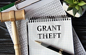 GRANT THEFT - words on a white sheet on the background of a judge\'s gavel, a cactus and a pen