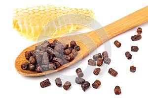 Granules of bee bread in a wooden spoon and a honeycomb are isolated on a white background. Apitherapy. Beekeeping