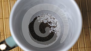 Granules of instant black coffee fall to the bottom of the white mug. Making coffee in the morning. The process of