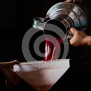Grape harvest, a man`s hands pour grape jiuce from a steel jug into a white funnel photo