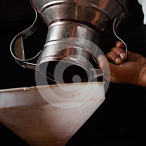 Grape harvest, a man`s hands pour grape jiuce from a steel jug into a white funnel photo