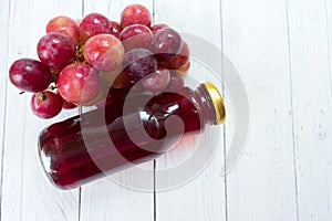 Grape juice in a bottle on a white wooden background.