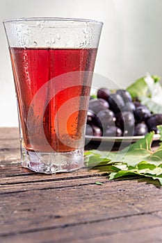 Grape juice and a cluster of grapes with green leaves.