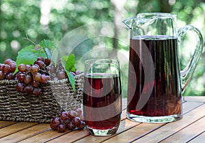 Grape juice in glass and pitcher with grapes in basket