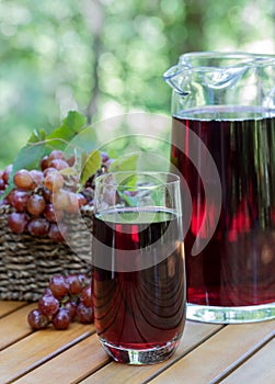 Grape juice in glass and pitcher with grapes in basket