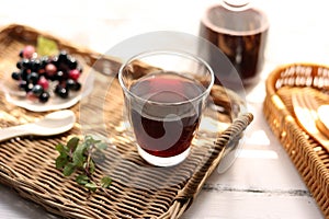 Grape juice poured into a glass on a rattan tray