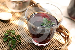 Grape juice poured into a glass on a rattan tray