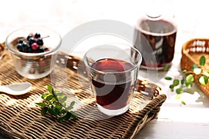 Grape juice poured into a glass on a rattan tray