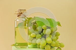 Grape seed oil.bottle and bunch of green grapes on podium on a beige background. Organic Natural Bio Grape Seed Oil.