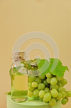 Grape seed oil.bottle and green grapes on podium on a beige background. Organic Natural Bio Grape Seed Oil.