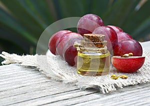 Grape seed oil in a glass jar and fresh grapes on old wooden table.Bottle of organic grape seed oil for spa and bodycare.