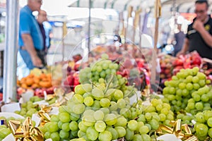 Grape on stall with selling fruit, food market, customers in background