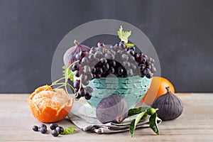 Grape, tangerine and figs fruit in blue bowl on wooden table, healthy food background. Diet, fructose and vitamin concept