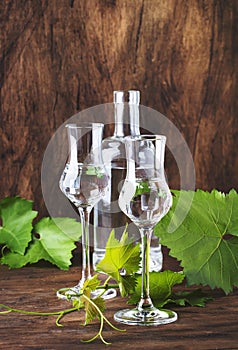 Grape vodka, pisco - traditional Peruvian strong alcoholic drink in elegant glasses on vintage wooden table, copy space