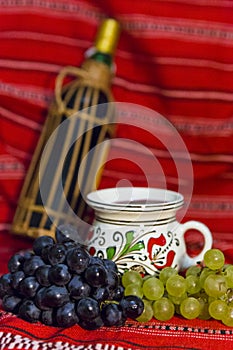Bottle of red wine, white and red grape, and a mug of wine