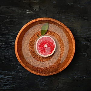 Grapefruit citrus fruit halves on wooden plate