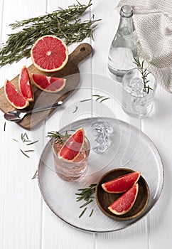 Grapefruit cocktail with rosemary on white wooden table