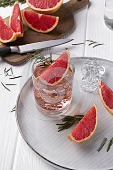 Grapefruit cocktail with rosemary on white wooden table