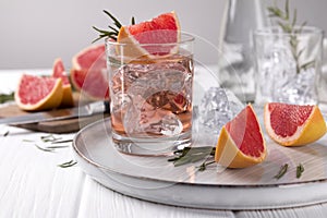 Grapefruit cocktail with rosemary on white wooden table