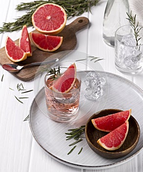 Grapefruit cocktail with rosemary on white wooden table