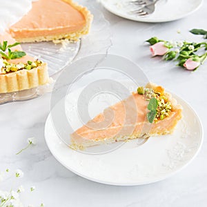 Grapefruit cream tart with pistachios and mint marble background