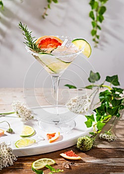 Grapefruit and cucumber, rosemary and lime cocktail, refreshing, cold drinks with ice on a rustic table. Summer garden party,